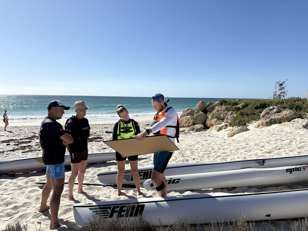 Coach giving technique feedback beside a paddler