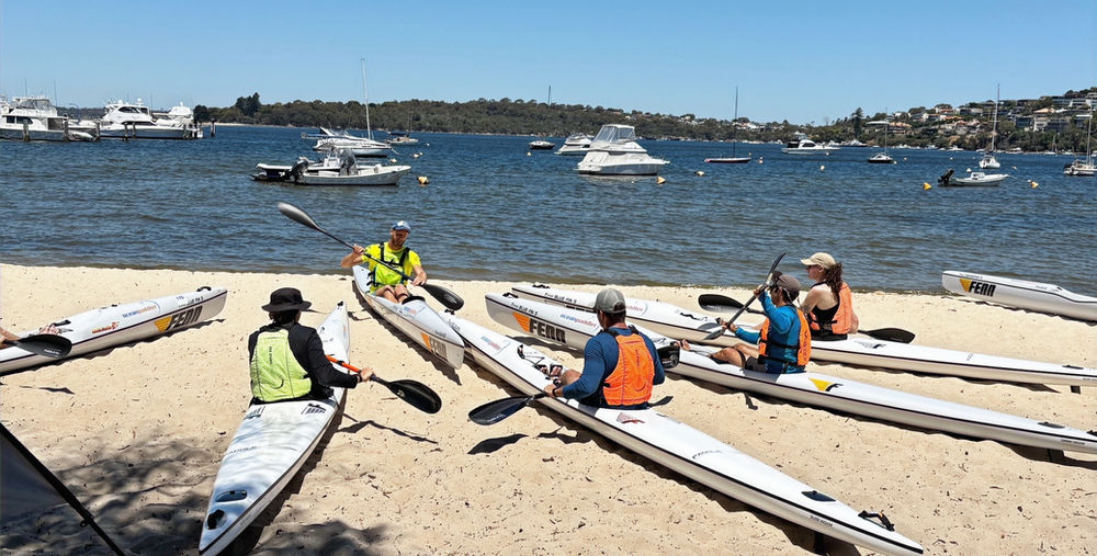 Beginner paddlers on calm water with a coach