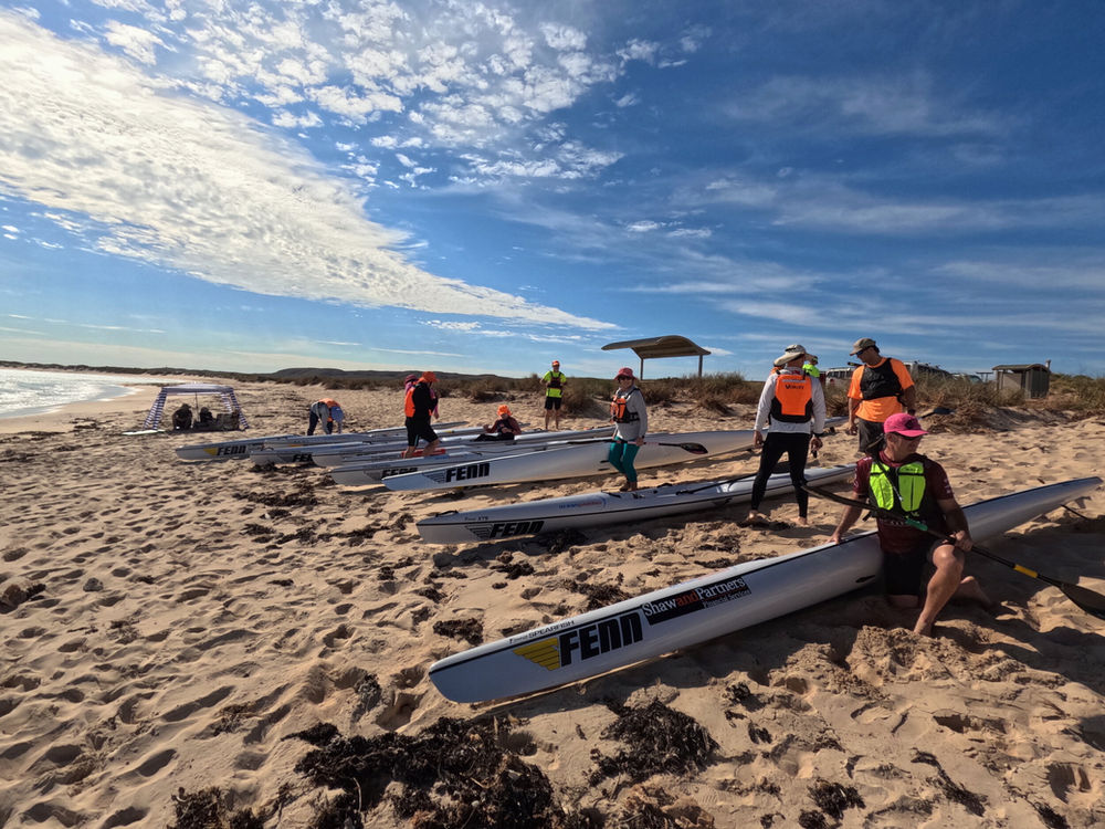 Coach briefing a group of paddlers on the beach